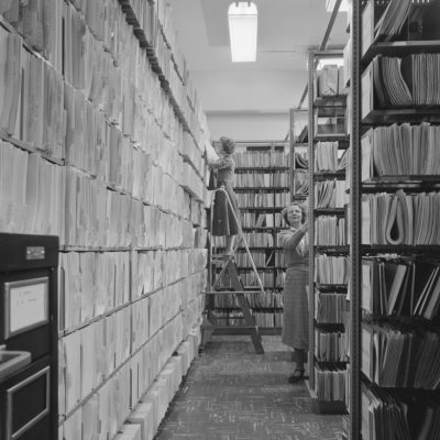 Information Division vault in Building 50 showing rows of file folders and documents on shelves. Photograph taken April 16, 1957. Principal Investigator/Project: Analog Conversion Project